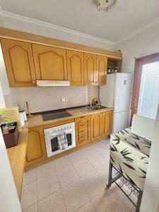 a kitchen with wooden cabinets and a white refrigerator at Villa Banfield in Gran Alacant