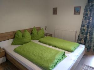 a bed with two green pillows on top of it at Wohnung Waldeslust In St Sigmund Im Sellrain in Sankt Sigmund im Sellrain +3 photos