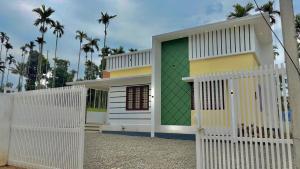 玛莱尤尔Maha Home Stay的一座白色大门和棕榈树的房子