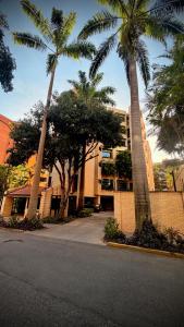 Un edificio con palmeras frente a una calle. en Apartamento en Campo Alegre, Chacao, Caracas, en Caracas