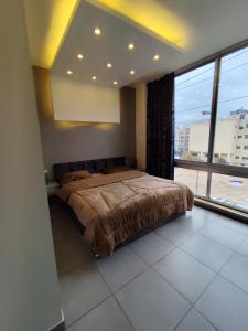 een slaapkamer met een bed en een groot raam bij Gentle Breeze Studio 3 in Amman