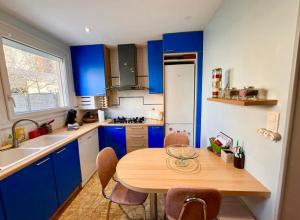 een keuken met blauwe kasten en een houten tafel bij Le Coquelicot - Centre - 8 Personnes - Parking in Le Mans