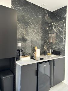 - une cuisine avec un mur en marbre noir dans l'établissement Charming Cozy Studio in Saint-Denis-Stade de France, à Saint-Denis