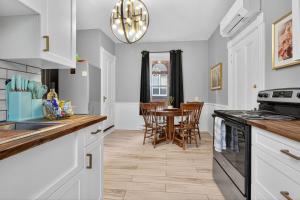 a kitchen with white cabinets and a table with chairs at Heritage House Downtown Moncton in Moncton