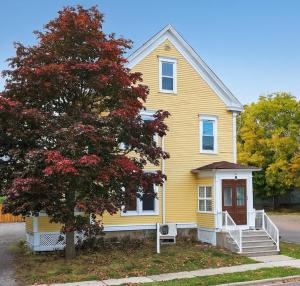 a yellow house with a tree in front of it at Heritage House Downtown Moncton in Moncton