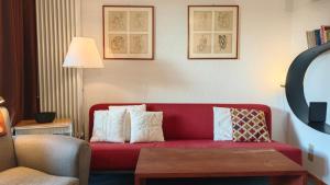 sala de estar con sofá rojo y almohadas en Hostdomus - Design Suite R10, en San Sicario 11 fotos más