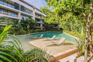 CedroにあるDivine 2BR with Beach Access Gym Fast WiFiの建物の前にスイミングプール(ラウンジチェア2脚付)