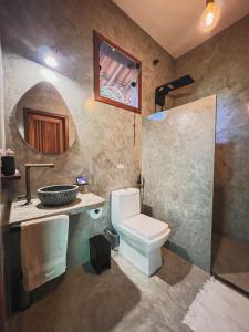 ein Badezimmer mit Toilette, Waschbecken und Spiegel in der Unterkunft Casa Gemini in Ilha de Boipeba