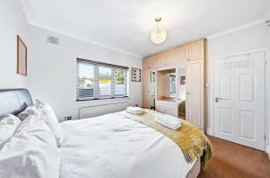 a bedroom with a large white bed and a window at Nancy's 3 bedroom house near Heathrow Airport in Hounslow