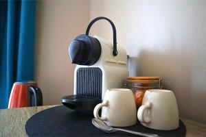 a table with two coffee mugs and a hair dryer at La Pause Voyage - chambre privative, gare à proximité in Bourbourg