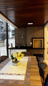 Una mesa con un jarrón de flores amarillas encima. en Conforto moderno na praia, en Itapema