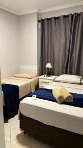 1 dormitorio con 2 camas y cortina en Conforto moderno na praia, en Itapema