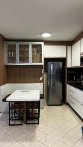 una cocina con una mesa y un refrigerador en Conforto moderno na praia, en Itapema