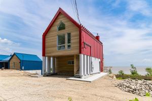 a small house with a red roof on the beach at Havre du Loup: St. Lawrence River Views & Trails in Petite-Rivière-Saint-François