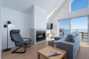 a living room with a couch and a chair and a fireplace at Panorama 1253: St. Lawrence View, Spacious Terrace in Petite-Rivière-Saint-François +6 photos