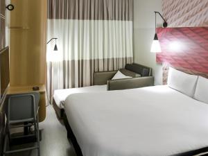 a hotel room with two beds and a chair at ibis Osasco in Osasco