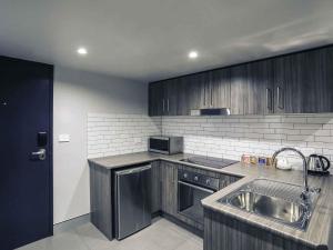 a kitchen with wooden cabinets and a stainless steel sink at Mercure Tamworth in Tamworth