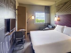 a hotel room with a large bed and a window at ibis Guaiba in Guaíba