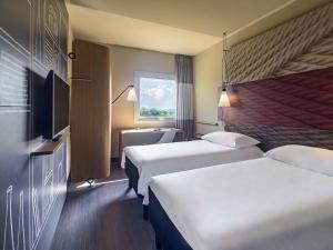 a hotel room with two beds and a window at ibis Guaiba in Guaíba