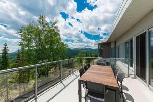 a balcony with a wooden table and chairs at Le Rupin 77: Luxury Contemporary, Spa, River View in Petite-Rivière-Saint-François