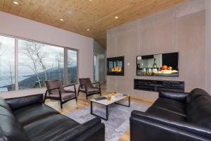 a living room with black leather furniture and a fireplace at Le Rupin 77: Luxury Contemporary, Spa, River View in Petite-Rivière-Saint-François