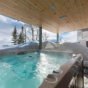 a hot tub with snow on top of it at Le Rupin 77: Luxury Contemporary, Spa, River View in Petite-Rivière-Saint-François