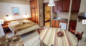 una camera con letto e tavolo e una cucina di Apartamento Esquina Rua Torta, Pousada do Serrano, Gramado, RS a Gramado