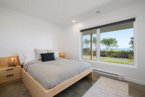 ein Schlafzimmer mit einem Bett und einem großen Fenster in der Unterkunft Mer et Mont 1223: Spa & River Views Near Le Massif in Petite-Rivière-Saint-François + 32 Fotos