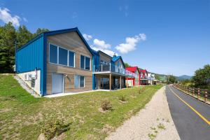 ein Haus auf einem Hügel neben einer Straße in der Unterkunft Mer et Mont 1223: Spa & River Views Near Le Massif in Petite-Rivière-Saint-François