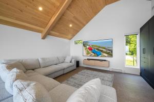 ein Wohnzimmer mit Sofa und Fernseher in der Unterkunft Mer et Mont 1223: Spa & River Views Near Le Massif in Petite-Rivière-Saint-François