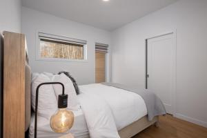 a bedroom with a bed with a lamp and a window at Panorama 1251: Fireplace & Unforgettable Views in Petite-Rivière-Saint-François