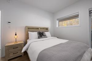 a white bedroom with a bed and a window at Panorama 1251: Private & Luxury, River Sunsets in Petite-Rivière-Saint-François