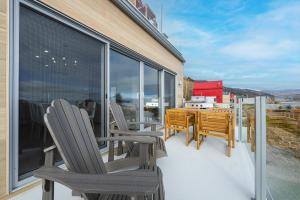 a balcony with chairs and a table and a window at Panorama 1251: Private & Luxury, River Sunsets in Petite-Rivière-Saint-François