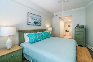 a bedroom with a blue bed with a lamp and a mirror at Sandpiper #108 in Tybee Island