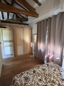 a bedroom with a bed with curtains and a wooden floor at La P'tite Maiz in Bourg-de-Visa +12 photos