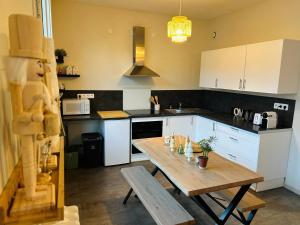 a kitchen with a wooden table and white cabinets at Le 5 - Spacieux 2 pièces Caen Centre Le Port in Caen +8 photos
