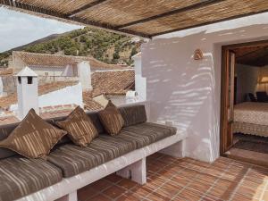 eine Couch auf einer Terrasse mit Blick auf ein Schlafzimmer in der Unterkunft Casa Al Zaytun Pueblo in Canillas de Aceituno