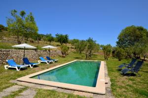 une piscine avec chaises et parasols dans une cour dans l'établissement Encantadora finca con piscina en la naturaleza, à Caimari