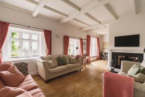 a living room with couches and a tv and a fireplace at 2 Hart Head Barn, Renovated Barn, Ambleside in Rydal