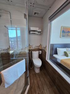 a bathroom with a toilet and a bed and a shower at La Maison in Cat Ba