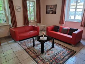 un salon avec deux canapés rouges et une table dans l'établissement Ferienwohnung Mit Garten Und Parkplatz, à Neumagen-Dhron