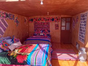 a bedroom with a bed with colorful blankets and pillows at Uros Titicaca UMA lodge in Puno