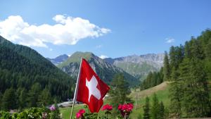 a red and white flag with mountains in the background at Sonnenhotel Soldanella Sonneck in Samnaun