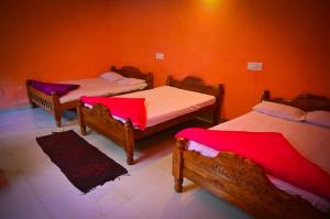 three beds in a room with orange walls at Green Palaces Homestay in Avathi +10 photos