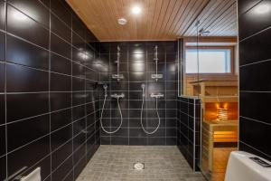uma casa de banho com um chuveiro com azulejos pretos em Penthouse Tampere & Jacuzzi hyvillä maisemilla em Tampere