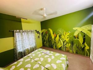 une chambre aux murs verts et un lit orné d'une fresque végétale dans l'établissement Hideaway villa, à Varkala