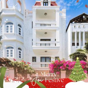 een kerstboom voor een wit gebouw bij Joi Home The Hidden Villa in Vung Tau