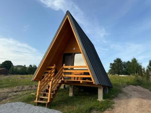 ein kleines Haus mit einem schwarzen Dach auf einem Feld in der Unterkunft A-Frame Haven in Dealu Muntelui