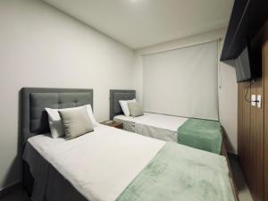 two beds in a small room with white walls at Studio Desing 3 - Alva in Maceió