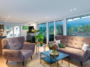 a living room with couches and tables and windows at Waldklang Panorama in Alpirsbach